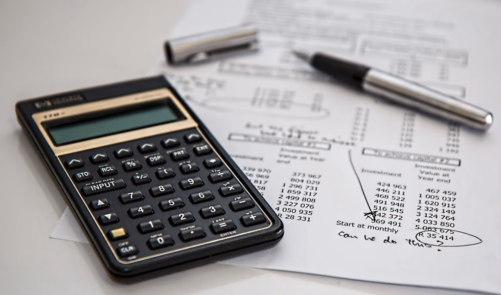 stock image of calculator laying on a printed bank statement with an uncapped ink pen in the background
