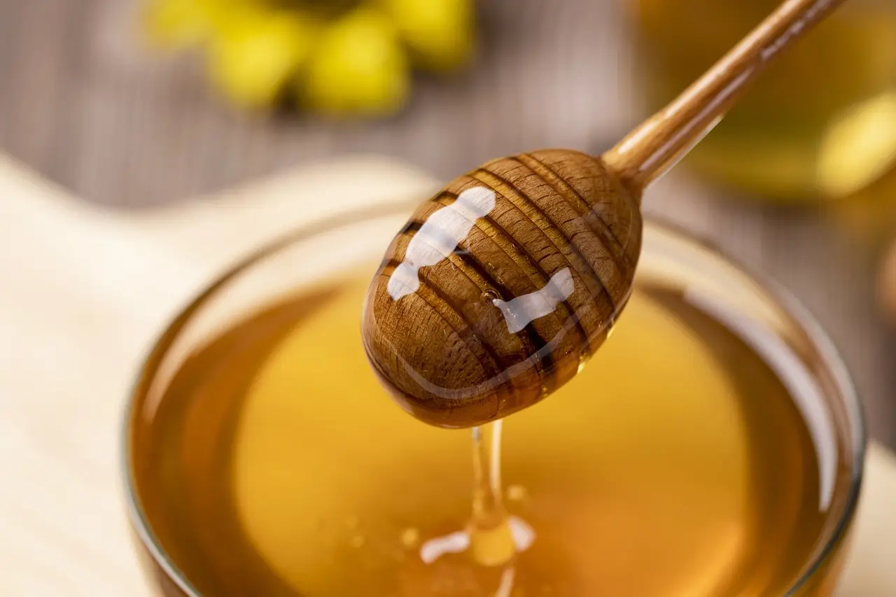 honey dipper being pulled out of a jar of honey